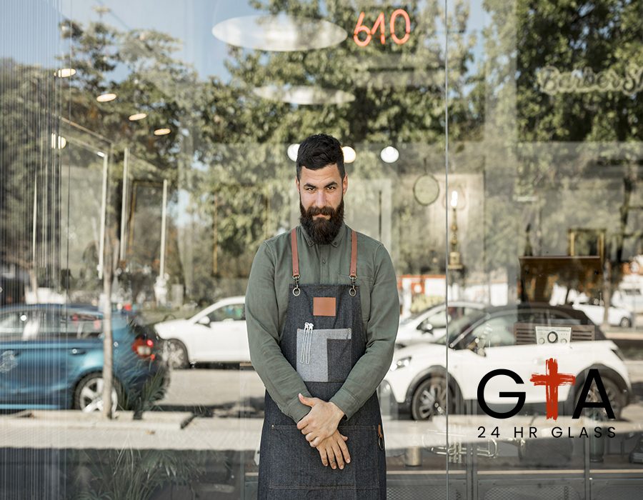 male-hairdresser-standing-near-barbershop-with-glass-walls