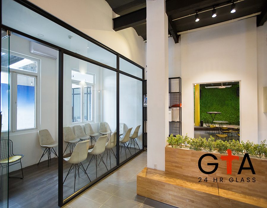 Nobody in office lobby with wooden bench. White wall with column and shelves. Green plants as part of interior. Many chairs behind glassy wall. Business center concept