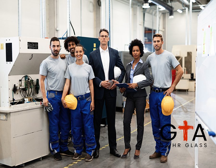 Portrait of group of engineers and corporate managers standing in a factory and looking at camera.