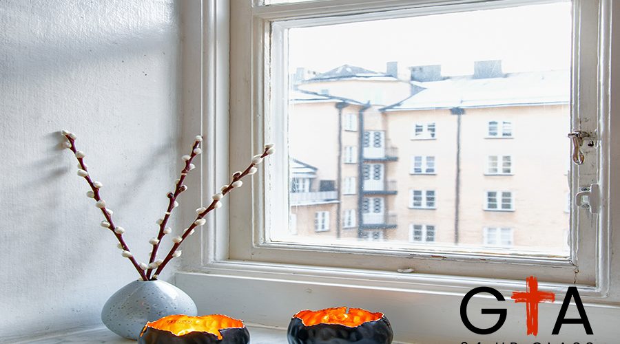 A vertical shot of two unique candle holders and a vase with a houseplant near the window