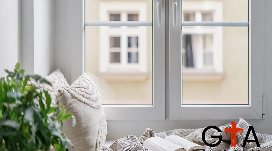 Windowsill with decorative cushions, soft plaid and open book in apartment with cozy interior. Comfortable place for reading on sill of window. Rest concept. Home decor idea