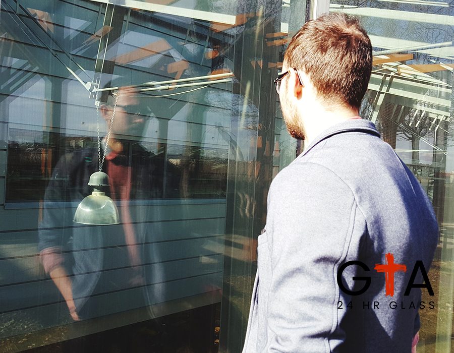 young-man-standing-by-store-window-sunny-day